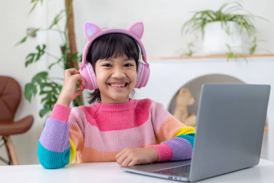 Girl sitting in front of a laptop - Feeling like you have enough homeschool time is achieved through mindset and practical steps  